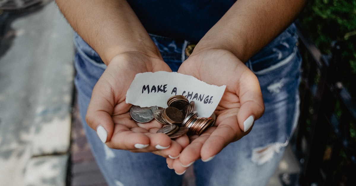 Hands holding coins with a note reading Make a Change