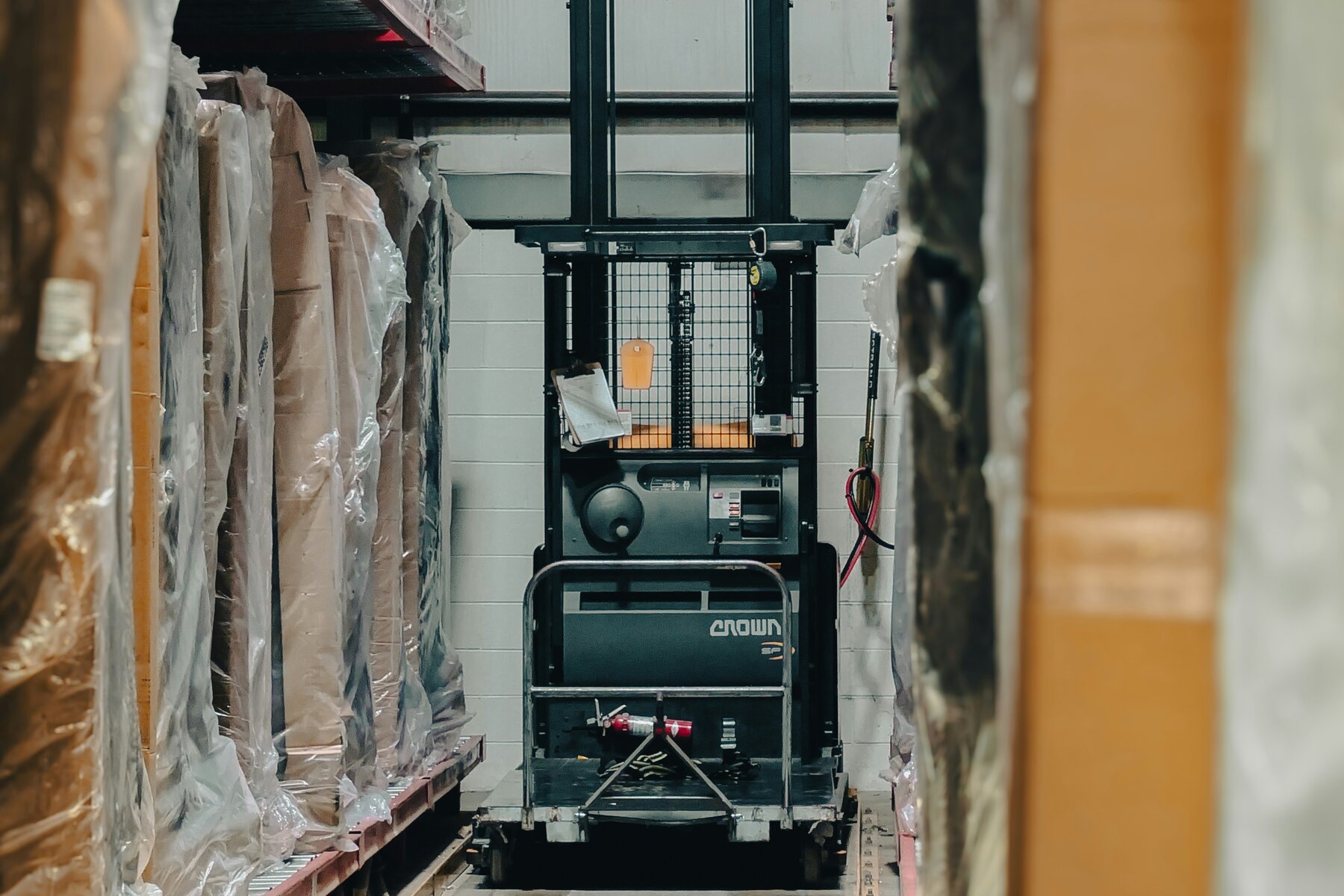 Forklift moving through a warehouse aisle between stored inventory